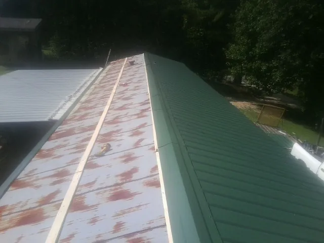 Old rusted panels beside newly installed green metal roofing — Wind Damage Roof Repair by Roofing Brothers in Montclair