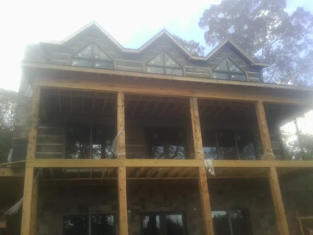 Dormers and porch framing on a large log home under construction — Roof Coating work by our crew in Montclair