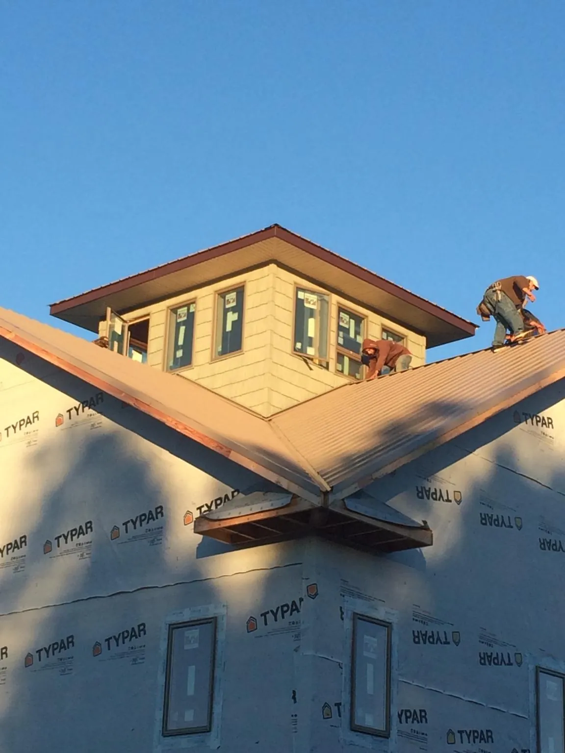 Roofers working around a rooftop cupola on a new metal roof at sunset — Roof Waterproofing in Montclair by Roofing Brothers